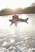 Ice skater sitting on ice, lake Ammersee, Upper Bavaria, Germany