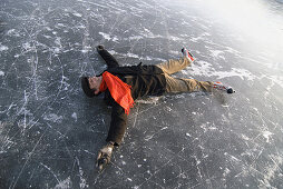 Schlittschuhläufer liegt auf dem Eis, Ammersee, Oberbayern, Deutschland