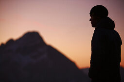 Junger Mann in den Bergen im Sonnenaufgang, Oberstdorf, Bayern, Deutschland