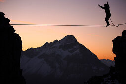 Man balancing on a rope in the afterglow, slackline in the mountains, Oberstdorf, Bavaria, Germany