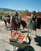 Eine Schubkarre mit Äpfeln und Männer auf Pferden vor einer Werkstatt, Texocuixpan, Provinz Tlaxcala, Mexico, Amerika