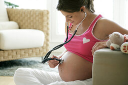 Schwangere Frau hält Stethoskop auf den Bauch