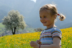 Blondes Mädchen auf einer Blumenwiese in den Bergen, Völs am Schlern, Südtirol, Italien, Europa