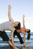 Young couple doing voga on the beach