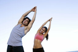 Young couple doing voga on the beach