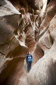 Female hiker stands in sandstone chamber in Little Wildhorse Slot Canyon, San Rafael Swell, Utah, USA