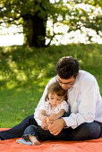 Vater und Tochter sitzen auf einer Wiese, Englischer Garten, München, Bayern, Deutschland