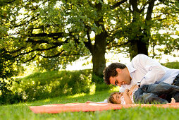 Father and daughter (2-3 years) playing on grass, English Garden, Munich, Bavaria, Germany