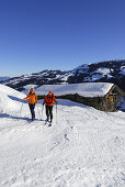 Two women backcountry skiing near alpine hut, Brechhorn, Kitzbuehel range, Tyrol, Austria