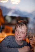 Zwei Jungen blicken aus einem Fenster, Brixen, Tirol, Österreich