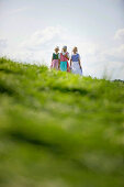 Three girls wearing dirndl in a meadow, Muensing, Bavaria, Germany