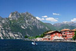 Blick über den Gardasee auf ein Straßencafe an der Promenade, Nago-Torbole, Trentino-Südtirol, Italien