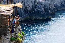 People fishing at the rocky coast in the sunlight, Capri, Italy, Europe