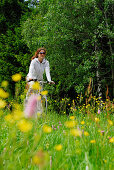 Radfahrerin fährt durch eine Blumenwiese, Nationalpark Bayerischer Wald, Niederbayern, Bayern, Deutschland