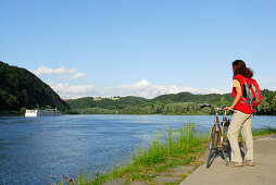 Female cyclist looking over river Danube, Danube Cycle Route Passau to Vienna, Passau, Lower Bavaria, Germany
