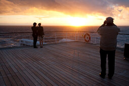 Young couple watching the sunset, Passenger on the afterdeck taking photographs, Cruise liner, Queen Mary 2, Transatlantic, Atlantic ocean
