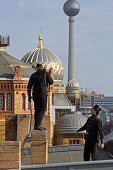 Chimney sweeps standing on roof, dome of New Synagogue, in background, Berlin, Germany