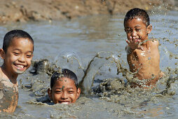 Drei Kinder, Jungen, beim Fischfang in schlammigem Graben, Lopburi, Zentralthailand, Thailand, Asien