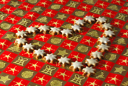 Weihnachtsgebäck Zimtsterne liegen in Herzform auf Geschenkpapier