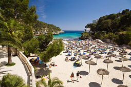 Menschen am Strand mit Sonnenschirmen in der Bucht Cala Santanyi, Mallorca, Balearen, Mittelmeer, Spanien, Europa