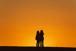 Zwei Frauen betrachten den Sonnenuntergang, Puerto de Tazacorte, UNESCO Biosphärenreservat, La Palma, kanarische Inseln, Spanien, Europa