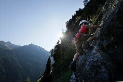 Junge (6-7 Jahre) klettert an einer Felswand, Pflerschtal, Südtirol, Trentino-Alto Adige, Italien