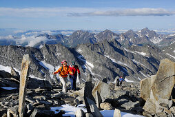 Drei Bergwanderer steigen zwischen Steinmännern zum Hochfeiler auf, Zillertaler Alpen, Südtirol, Italien
