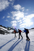 Drei Bergwanderer steigen über ein Schneefeld zum Hochfeiler auf, Zillertaler Alpen, Südtirol, Italien
