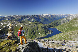 Woman looking over reservoir Lago della Sella to Ticino Alps, Gotthard range, Canton of Ticino, Switzerland