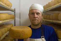 Käselager in der Käserei auf dem Gut Adolphshof bei Lehrte-Hämelerwald, Mitarbeiter überpüft die Käse, Regale gefüllt mit Käse