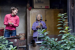 Old chinese woman and german tourist at the courtyard of a roundhouse of the Hakka, Hongkeng, Longyan, Fujian, China, Asia