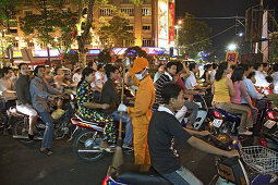 Menschen fahren auf Motorrollern während des Tet Fests bei Nacht, Saigon, Ho Chi Minh Stadt, Vietnam, Asien