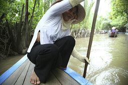 Woman with paddle in a boat on a canal, Mekong Delta, Vietnam, Asia