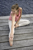 Young woman stretching on a jetty at lake Starnberg, Bavaria, Germany