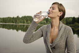 Junge Frau trinkt eine Flasche Wasser, Starnberger See, Bayern, Deutschland