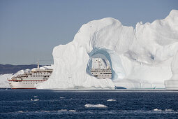 Kreuzfahrtschiff MS Deutschland (Reederei Peter Deilmann) hinter Eisberg mit Loch vom Ilulissat Kangerlua Isfjord, Ilulissat (Jakobshavn), Diskobucht, Kitaa, Grönland