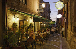Guests sitting outside a restaurant in the evening, Cefalu, Sicily, Italy