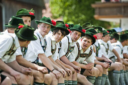 Junge Männer in Tracht sitzen nebeneinander, Mailaufen, Antdorf, Oberbayern, Deutschland