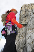 Woman with climbing gear and climbing rope reading a guidebook, Massa, Tuscany, Italy
