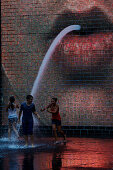 Teenagers playing in The Crowne Fountain by Jaume Plensa, Millenium Park, Chicago, Illinois, USA