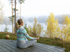 Woman meditates on terrace, Skane, Sweden