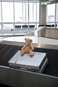 Suitcase and teddy bear on baggage conveyor belt, Munich airport, Bavaria, Germany