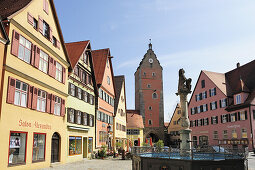 Fountain in front of a row of houses and Woernitztor city gate, Dinkelbuehl, Bavaria, Germany