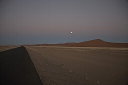 Asphalt road in Namib Naukluft Park at full moon, Sossusvlei, Namibia, Africa