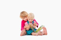 sisters looking at chidren's book - isolated on white