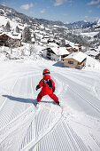 Child skiing on fresh primed ski piste, Schlosslelift, view to Hirschegg, Kleinwalsertal, Vorarlberg, Austria