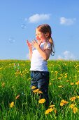 girl playing with bubbles in field of Dandelions, Zuercher Oberland, Zuerich, Switzerland