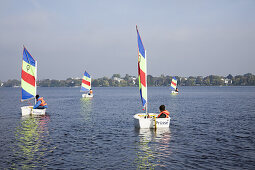 Children in sailing dinghies on outer Alster, Hamburg, Germany