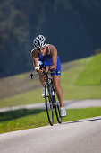 Woman cycling with a triathlon bike on road near Munsing, Upper Bavaria, Germany