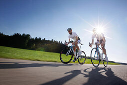 Two racing cyclists on road near Munsing, Upper Bavaria, Germany